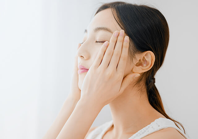 両頬に手を当てている肌の綺麗な女性